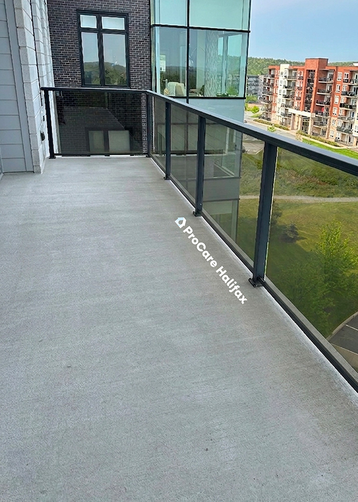 Clean and restored light grey concrete balcony surface with all furniture removed and glass railing intact